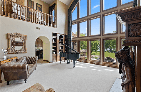 Expansive Great Room with fireplace, piano, and views of the scenic landscape at Mansion on the Lake in Newton, WI, perfect for family gatherings and relaxation