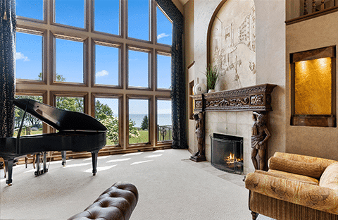 Expansive Great Room with fireplace, piano, and lake views at Mansion on the Lake in Newton, WI, perfect for family gatherings and relaxation