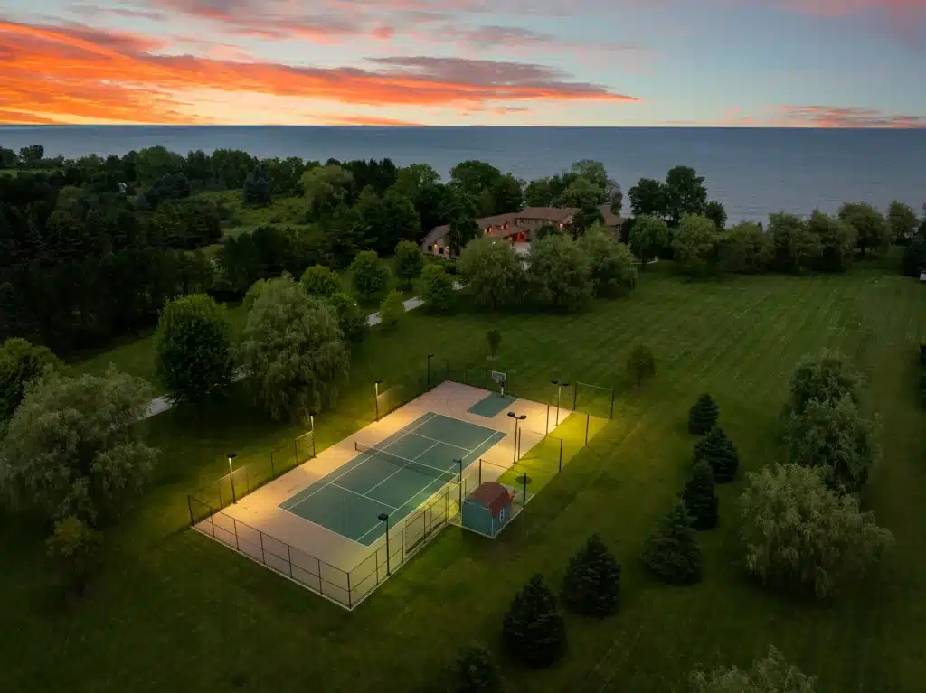 Drone shot of Mansion on the Lake in Newton, WI, showcasing Lake Michigan, tennis court, and expansive property grounds with luxury amenities