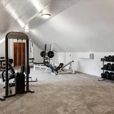 Fully equipped workout room at Mansion on the Lake with treadmill, weight bench, leg press, exercise machines, and large windows with natural light