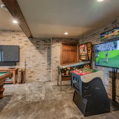 Game room at Mansion on the Lake with pool table, dartboard, TV, Cyclone and Golden Tee arcade games, and seating area