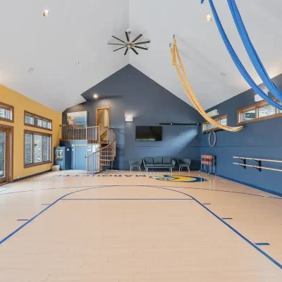 Indoor basketball court at Mansion on the Lake with access to the outdoor pool, spiral staircase to the main floor, two TVs, and seating area
