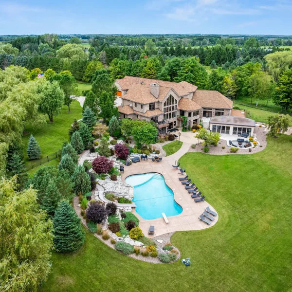 Drone view of Mansion on the Lake showing entire property with outdoor pool, backyard, and summer house in Newton, WI