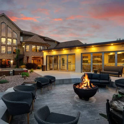 Back view of Mansion on the Lake facing Lake Michigan, with hot tub, outdoor fireplace, and summer house with full kitchen and covered area for gatherings