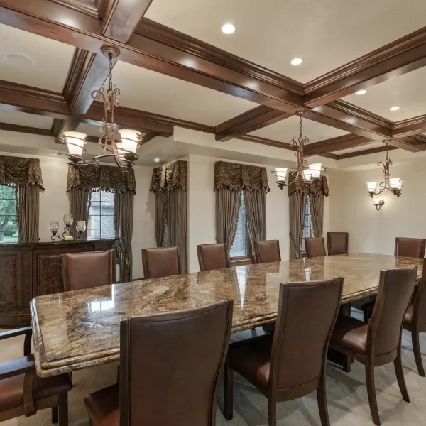 Full view of the Mansion on the Lake dining room with a grand table, plush chairs, bar area, and large windows overlooking the landscape.